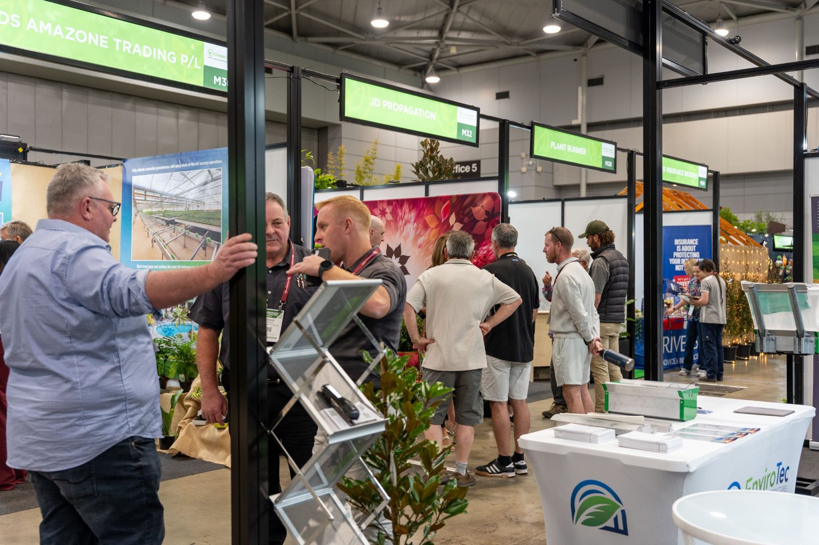 Exhibitors talking with visitors along a busy aisle